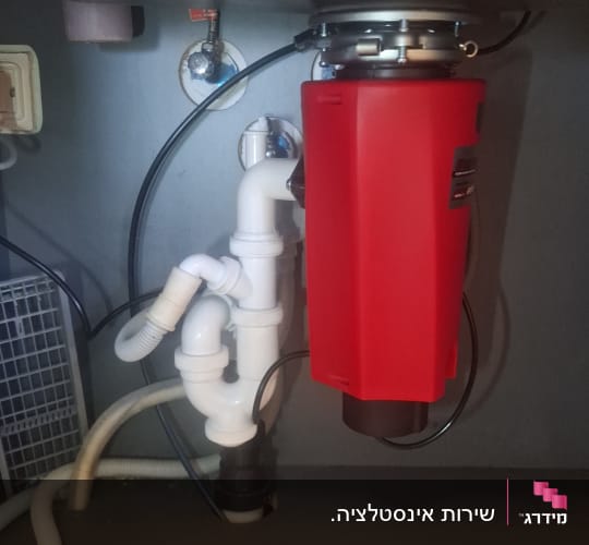 מתקן אינסטלציה מתחת לכיור עם צינורות ומחבר אדום